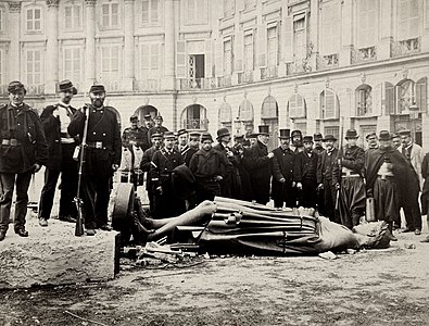 Comuneros alrededor de la estatua del emperador Napoleón I en el suelo.