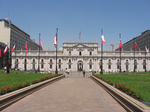 A palace with several flagpoles with flags of Chile in front