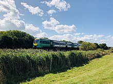 Shot of a field with a train running along a straight track in the distance