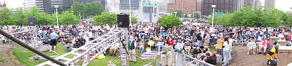 Photo panoramique d'une foule avec des immeubles en arrière plan.