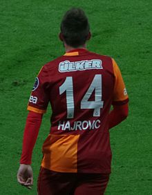 Homme, de dos, portant un maillot de football, avec deux larges rayures verticales rouge et orange