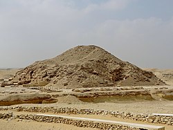 A ruined mass of bricks, sand and rocks resembling an earthen mound