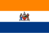 A flag with three equal horizontal stripes colored orange, white, and blue from top to bottom. In the center is the city seal (except for text and circular outline).