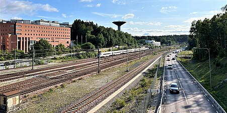 Huddingevägen vid Flemingsbergs station, med bland annat Flemingsbergs vattentorn i bakgrunden, 2023