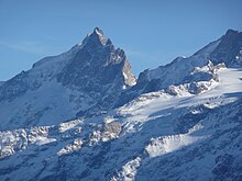 Vue d'un sommet grossièrement pyramidal et déchiqueté dans un environnement de neige et de glace.