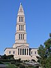 A granite memorial building with a wide base two stories high, columns in front, and a seven story tower topped by a pyramid and light