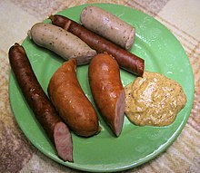 Several kielbasas on a plate with mustard