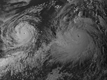 A satellite image of two powerful hurricanes over the Eastern Pacific. One is larger than the other, but both are very well-organized with tightly wound circulations, clear eyes, and thick, deep clouds.