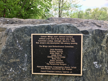 The text reads, "Samuel 'Mingo Jack' Johnson lynched without a fair trial at the former site of the Eatontown Lockup, midnight, March 5, 1886. New Jersey's only documented 19th century lynching. The Mango Jack Remembrance Committee: Inice Hennessy, Rodney Jackson, Alden Small Sr., James Stone, Carolyn Storey-Hodge, Rose Terry, Sonny Thornton, Sondra Thompson, The Paranormal Rangers. Honorary Members: Congregation Shaare Tefilah Bene Moshe, Councilman Meir Araman.