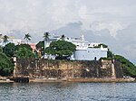 A blue fortress and stone walls above a bay