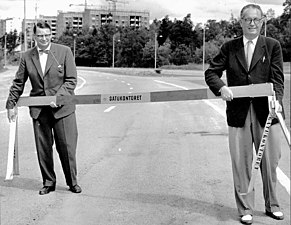 Stadsarkitekt Evert Trovik och borgarråd Helge Berglund öppnar Nya Huddingevägen i juli 1959. I bakgrunden syns flerfamiljshus på Olshammarsgatan under uppförande.