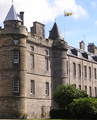 The Royal Standard of the United Kingdom used in Scotland, featuring the Royal Banner of Scotland in the first and fourth quarters, flying over the Palace of Holyrood House, Edinburgh.