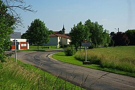 Photographie de l'entrée du village avec le panneau indicateur.