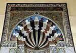 Mihrab com motivo central do "nascer do sol" e mosaicos de vidro nos tímpanos acima, na Madraça Taibarcia (1304) na Mesquita de Al-Azhar.