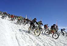 Vue d'une foule de VTTistes dévalant une pente enneigée.