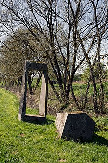 Nikolaus Gerhart, Kern und Hülle, 1986/89, Kern 100 × 100 × 210 cm, Hülle 288 × 118 × 100 cm, Basaltlava, Bachlauf. Standort: im Tal (Skulpturenpark) zwischen Hasselbach und Werkhausen