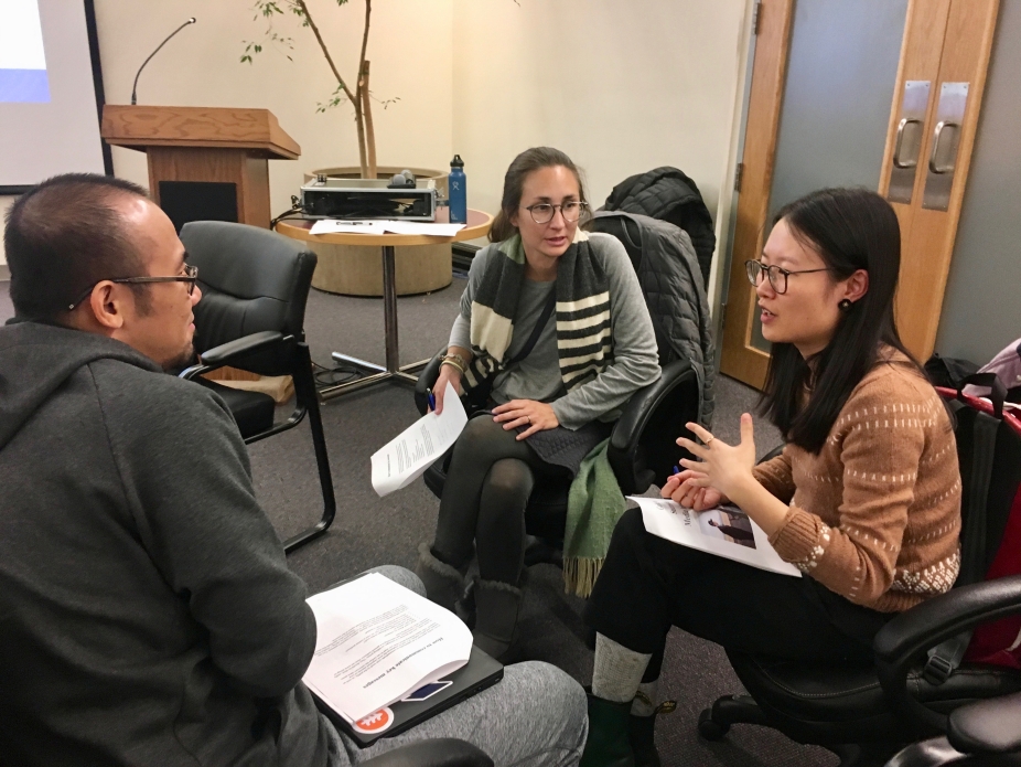 Three students sit in chairs in a circle and talk during a training