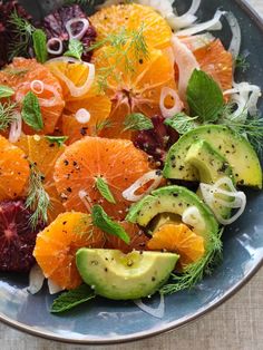 a bowl filled with oranges, avocado and other food on top of a table