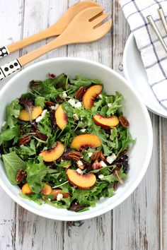 a salad with peaches, feta cheese and pecans in a white bowl