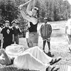 Demonstrating that his PerkiSystem total fitness program builds strong bodies, health nut Tony Perkis (Ben Stiller, supine) proves his point on a bed of nails as the awestruck campers witness Lars (Tom Hodges, center) smashing a block of ice on Tony's brick-hard stomach.