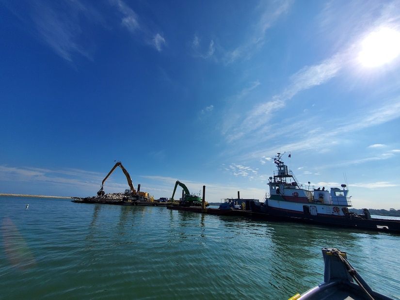 A tug boat next to construction equipment on water.