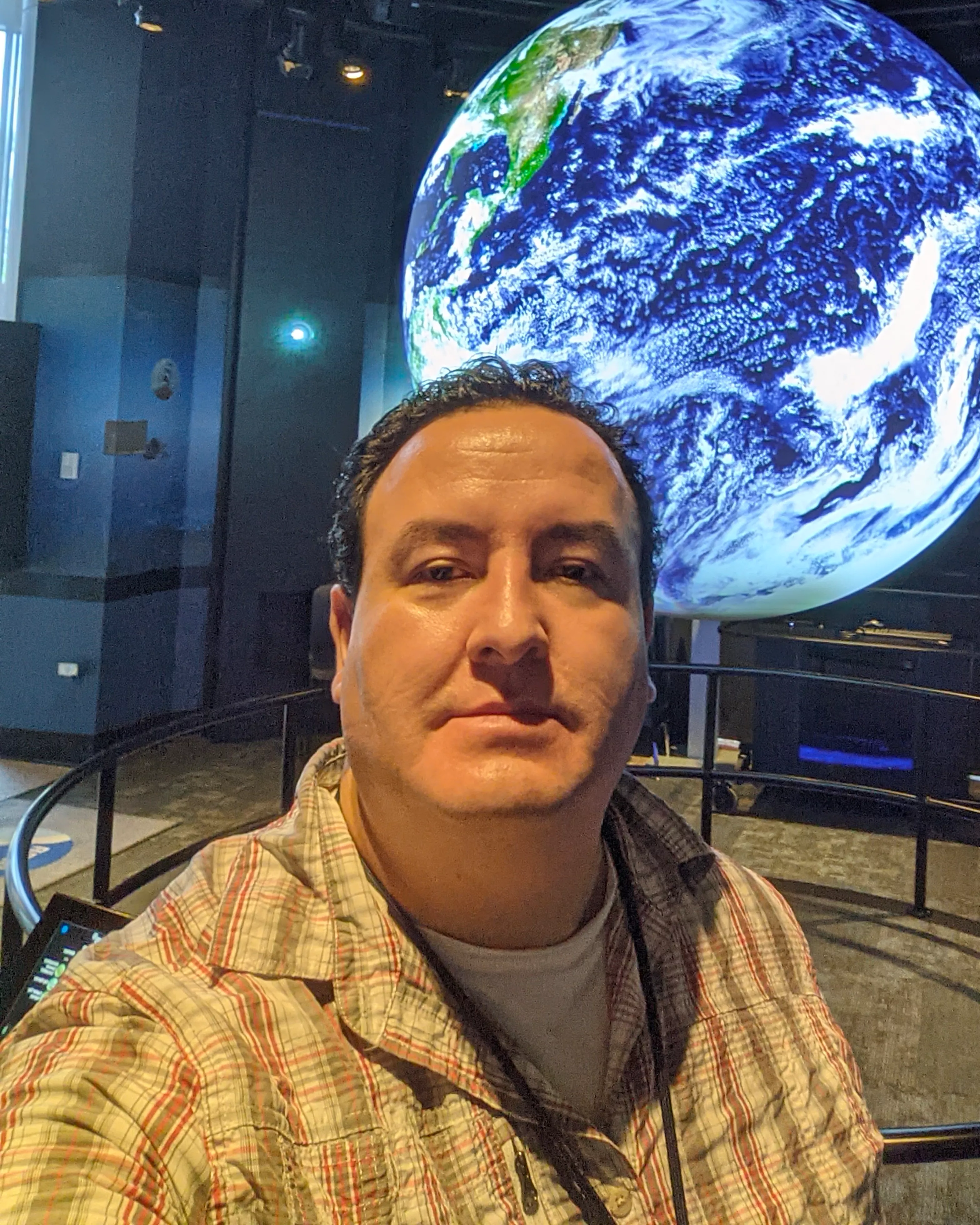 Juan Pablo standing in front of a very large Earth.