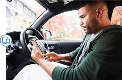 A person sitting in a car looking at a smart phone.