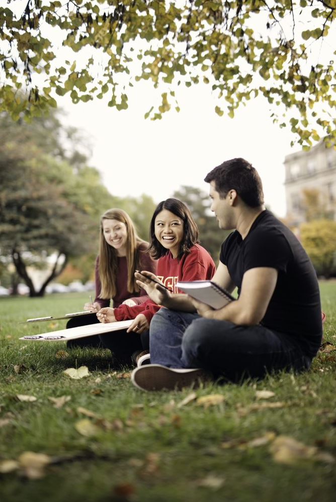 Three students with drawing boards, working on Architectual projects outside, sitting on one of ISU's lawns