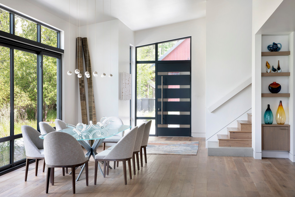 Example of a trendy medium tone wood floor, brown floor and vaulted ceiling great room design in Other with white walls