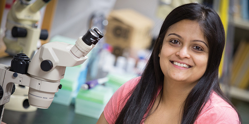 Student in a science lab next to a microscope