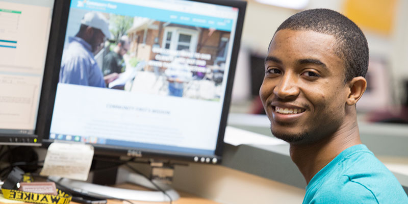 Student working on a computer, looking toward the camera