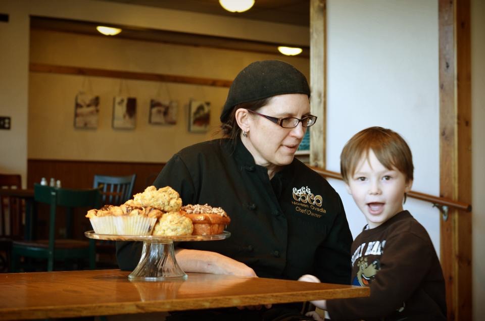 Woman and child sitting at a table with pastries on a plate.