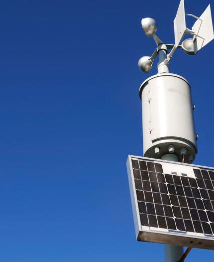 A solar powered weather station on a pole.