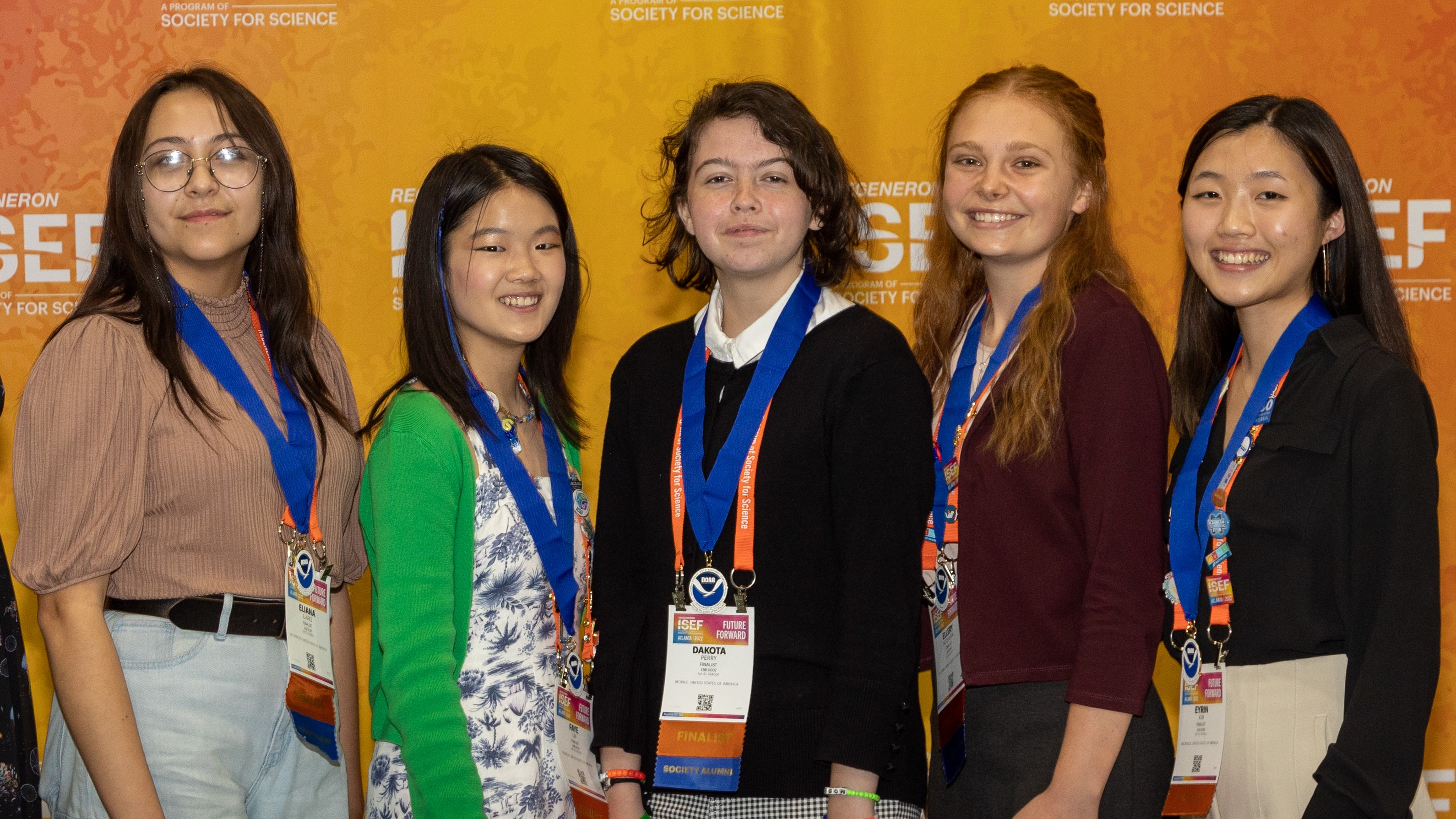 Five smiling high school students wearing NOAA award medals stand in front of an orange background. 